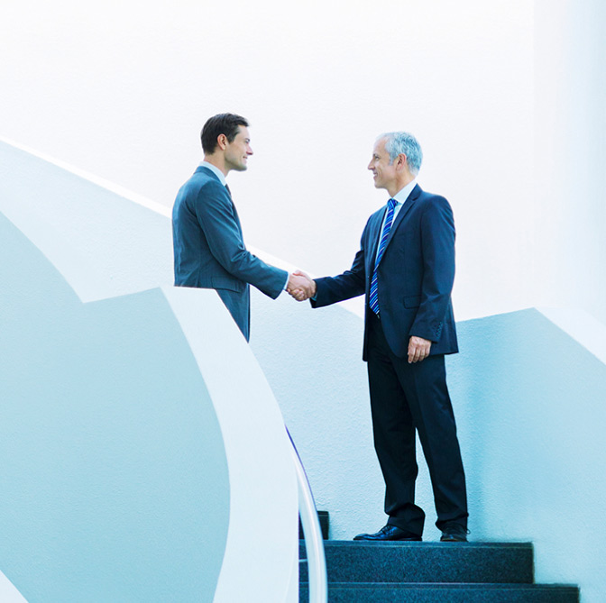 Business managers shaking hands on stairs.